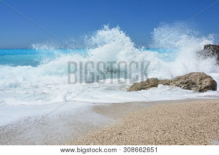 Summer Concept, Big, Splashing Waves And  Rocks In Shallow Sea, Turquoise Water And Clear Sky Over F