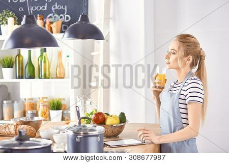 The Girl At The Table In The Kitchen With A Glass Of Orange Jui