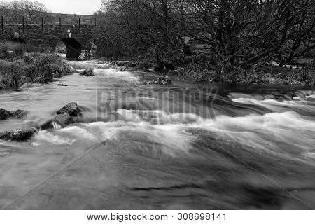 Black And White Image Of The River Lyd Running Under The B3357 On Dartmoor, Landscape Aspect With Sl