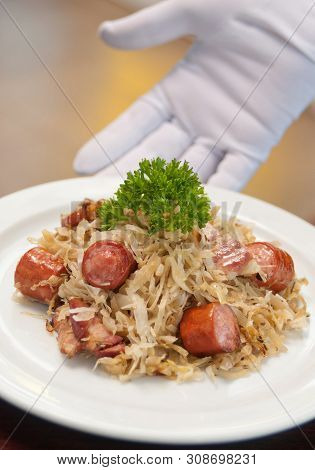 German, Polish, Austrian Cuisine Dish, Bigos - Cabbage Stewed With Meat And Sausages On A White Plat