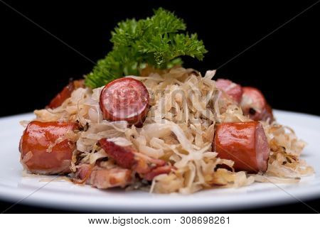 German, Polish, Austrian Cuisine Dish, Bigos - Cabbage Stewed With Meat And Sausages On A White Plat