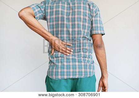 African Man With Pain In Kidneys Isolated On A Gray Background. Man With Back Ache Clasping Her Hand