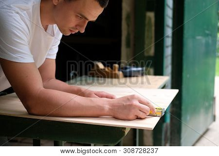 Carpenter Marking Straight Line On Plywood Sheet Using Spirit Level In Carpentry Workshop. Measuring