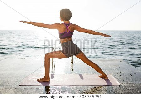 Woman With Short Hair Pulling Hands Aside While Training Yoga Poses By The Sea