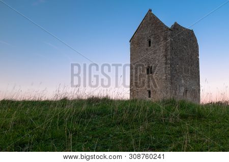 The Grade Ii Listed Dovecote Tower At Bruton In Somerset Shot At Sunset, Low Angle Through The Grass