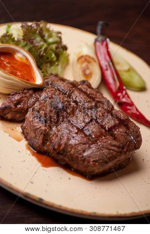 Well-done Steak With Suace And Vagetables. Reastaurant Dishes On The Wooden Table. Food Photo For Re