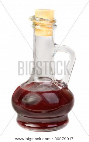 Kleine Karaffe mit Rotwein-Essig auf dem weißen Hintergrund isoliert