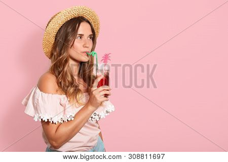 Studio Shjt Of Young Beautiful Woman, Posing In Shirt With Bare Shoulders And Straw Hat, Drinking Tr