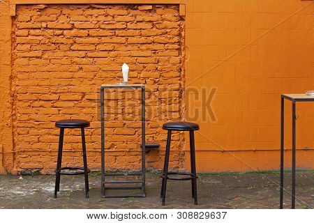 Black Bar Chairs And Orange Brick Floor Laid In Fishbone Style, Covered With Moss. Hipster Retro Sty