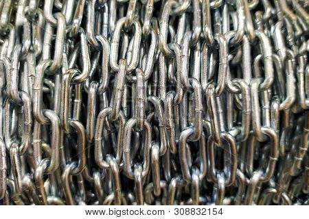 The Steel Chain Is Reeled Up On The Big Coil. The Shining Long Industrial Chain Twisted In A Roll. T
