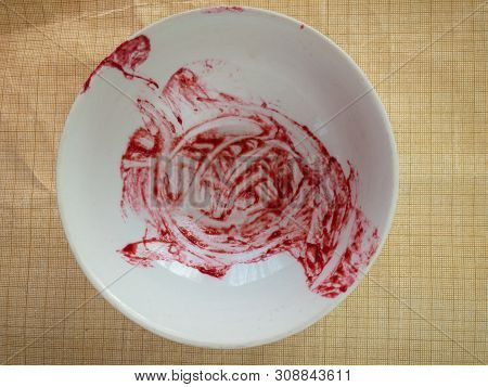 White Empty Bowl With Raspberry Mash Leftovers Standing On Crumped Graph Paper Surface
