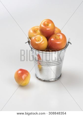 Berries Of Yellow-pink Cherry In A Chrome-plated Silver Metal Bucket And One Near It, Close-up On A 