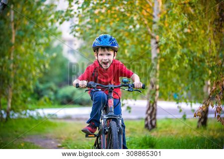 A Small White Toddler Boy In A Protective Helmet On His Head Sits On A Children's Bicycle. Toddler O