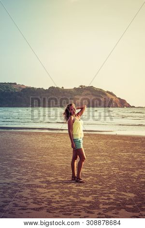 Girl Walking Along The Beach At Sunset