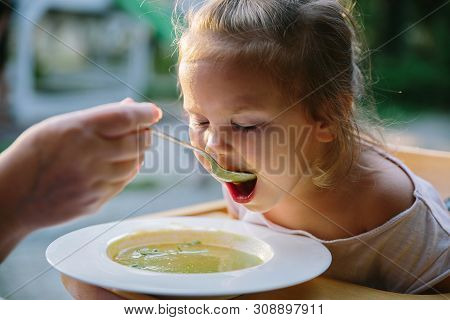 Child Feading With Soup At The Restaurant Garden