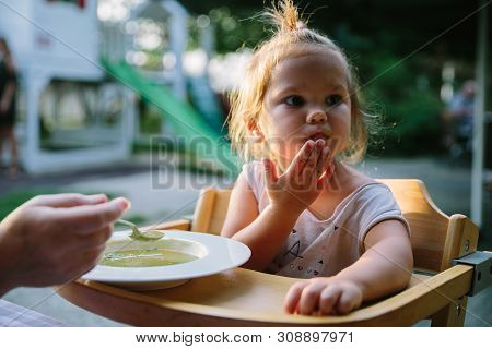 Child Feading With Soup At The Restaurant Garden