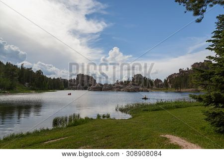 People In Small Boats Enjoy The Calm Waters Of Sylvan Lake With Its Dynamic Granite Rock Features On