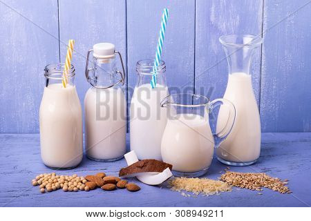 Types Of Vegetable And Organic Milk In Glass Containers On A Light Blue Wooden Table