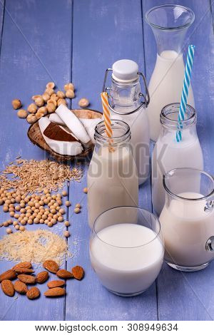 Types Of Vegetable And Organic Milk In Glass Containers On A Light Blue Wooden Table