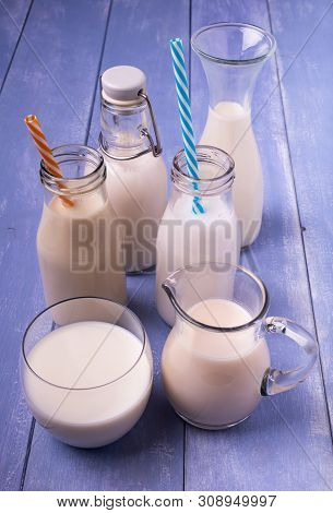 Types Of Vegetable And Organic Milk In Glass Containers On A Light Blue Wooden Table