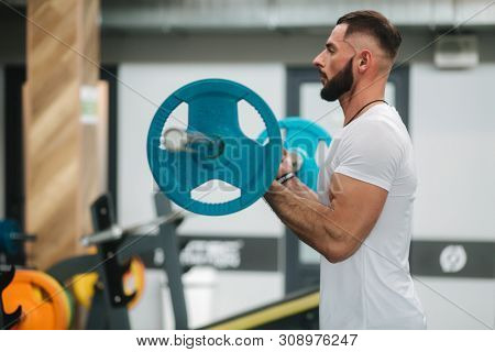 A Young Athlete Trains In The Gym. Trians Biceps Muscules