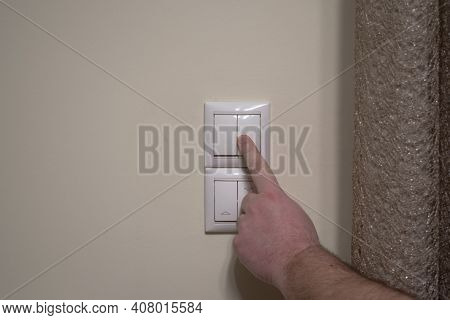 Finger Pressing Light Switch To Turn Off The Light. Modern White Light Switch On White Wall