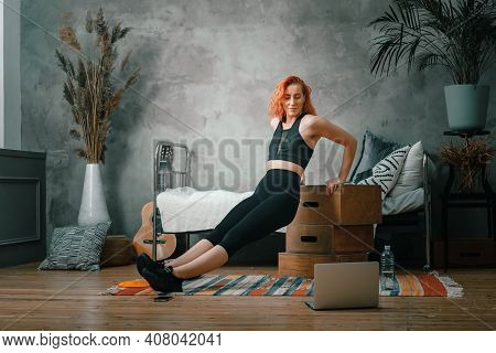 The Beauty Woman Goes In For Sports At Home. Cheerful Sporty Woman With Red Hair Shakes Biceps, Do P