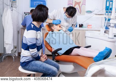 Dentist In The Course Oral Treatment For Little Kid With Caries. Dentistry Specialist During Child C