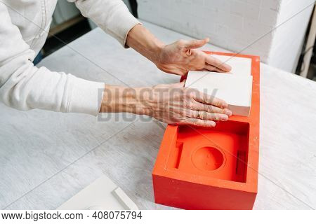 Hands Taking Freshly Made Gypsum Plaster Mold Out Of The Casting Form.