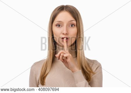 Portrait Of Young Blond Woman Keeping Finger At Her Mouth, Saying Shh, Hush, Tsss. Silence And Secre