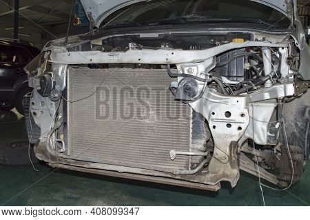 The Gray Car With The Front Bumper Removed Is In The Auto Repair Shop. The Radiator And Chassis Elem