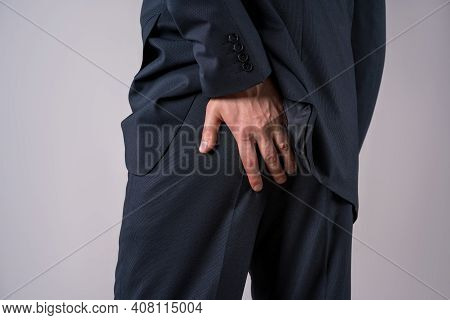 Office Worker Suffering From Hemorrhoids, Anal Pain On Gray Background