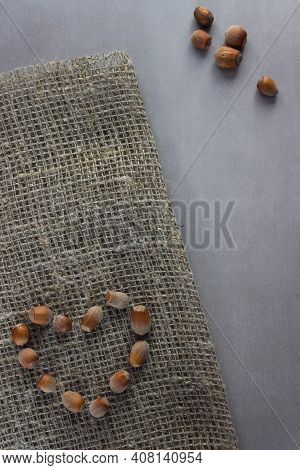 Nuts Laid Out In The Shape Of A Heart On Burlap With Nuts Heap Nearby On Gray Background. Organic, H