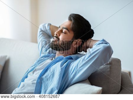 Relax Time. Portrait Of Handsome Arab Man Leaning Back On Couch With Closed Eyes, Keeping Hands Behi