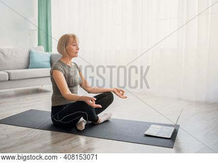 Peaceful Senior Woman Meditating With Closed Eyes In Front Of Laptop Computer At Home, Copy Space. C