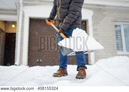 A Mature Man Clean Path Near House From Snow During Strong Blizzard. Person Shoveling Snow Out Of Th