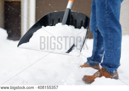 A Mature Man Clean Path Near House From Snow During Strong Blizzard. Person Shoveling Snow Out Of Th