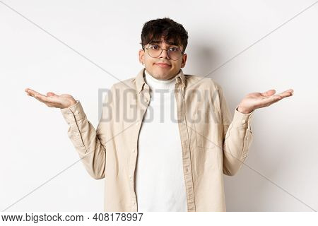 Portrait Of Handsome Young Man Looking Confused, Know Nothing, Shrugging Shoulders And Spread Hands 