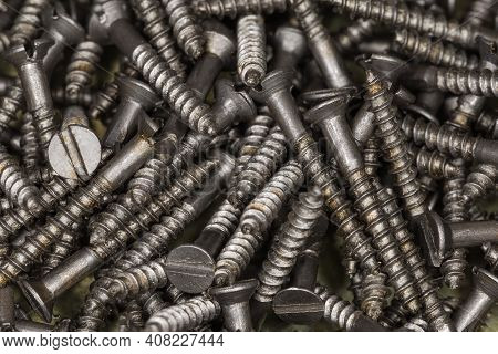 Pile Of Steel Countersunk Slotted Wood Screws With Partially Unthreaded Shank, Top View Close-up In 