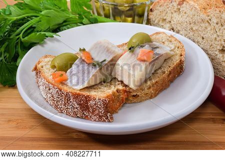 Open Sandwich Made With Whole Wheat Bread, Slices Of Pickled Atlantic Herring Fillet And Green Olive