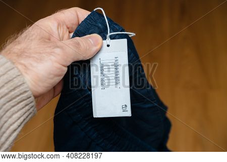 Pov Male Hand Holding New Pair Of Pants With Price Tag In Multiple International Currencies And Rfid
