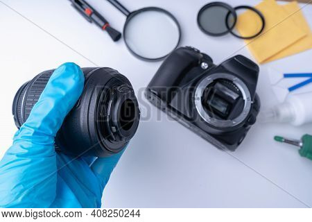 The Hand Of The Master In Blue Gloves Removes The Lens Of The Dslr Camera Before Cleaning The Matrix