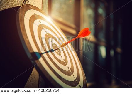 Dart Arrow Hit On Bulleyes Of Dartboard To Represent That The Business Reached The Target  With Dark