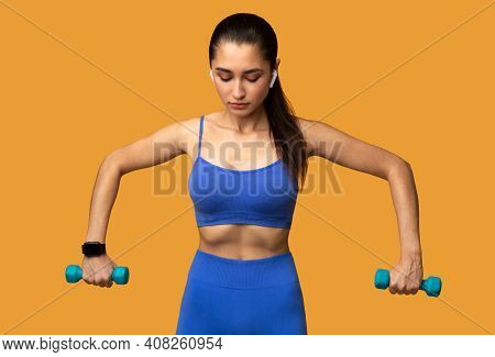 Biceps Exercises, Arms Workout. Determined Young Lady In Wireless Earphones Doing Training With Two 