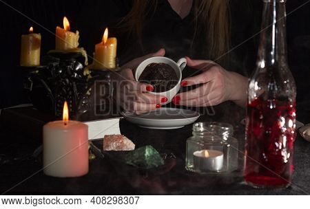 Fortune-telling On Coffee Grounds. A Fortune Teller's Hands, A Cup Of Coffee, Candles, And Skulls On