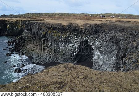 Iceland's Black Sand Beach And Basalt Column Cliffs.