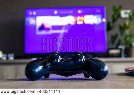 A Portrait From Behind A Sony Playstation 4 Controller In Front Of A Television With The Playstation