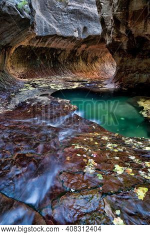 Vertical of green pool, flowing water and a circular rock formation at the Subway, a unique tunnel scuplted by the Left Fork of North Creek in Zion National Park, Utah