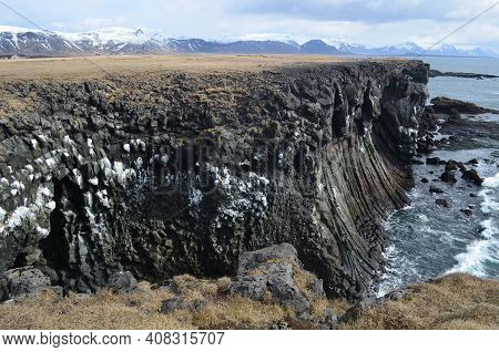 Stunning View Of Rock Cliffs, Basalt Columns And Snow Covered Mountains.