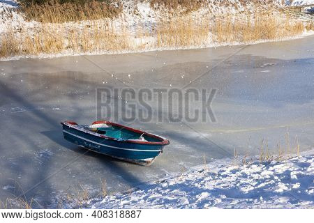 Frozen Ditch With Wooden Rowing-boat Lying On The Ice